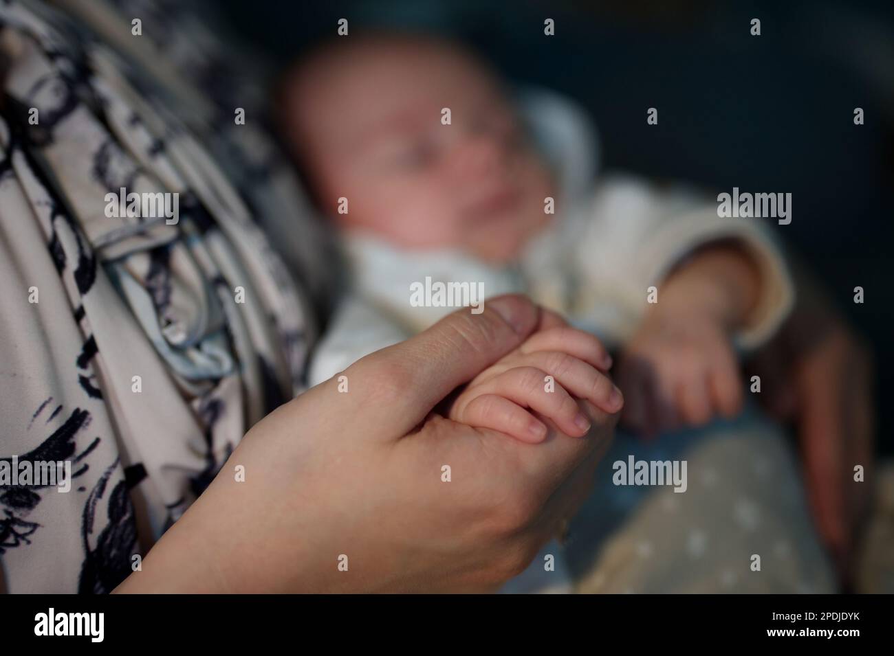Closeup of newborn baby's hand holding mother's finger Stock Photo
