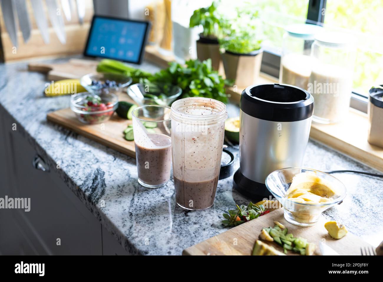 High angle view of smoothie in drinking glass and blender with fruits on kitchen counter, copy space Stock Photo