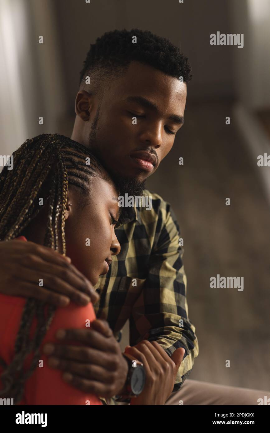 Sad african american couple sitting and embracing in hall Stock Photo