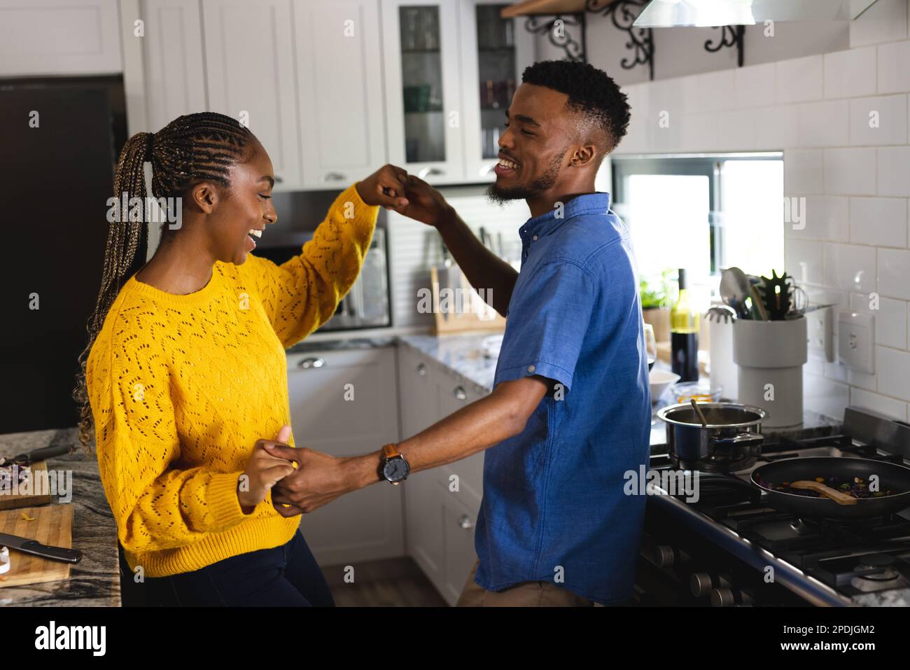 Happy african american couple holding hands and dancing in kitchen ...