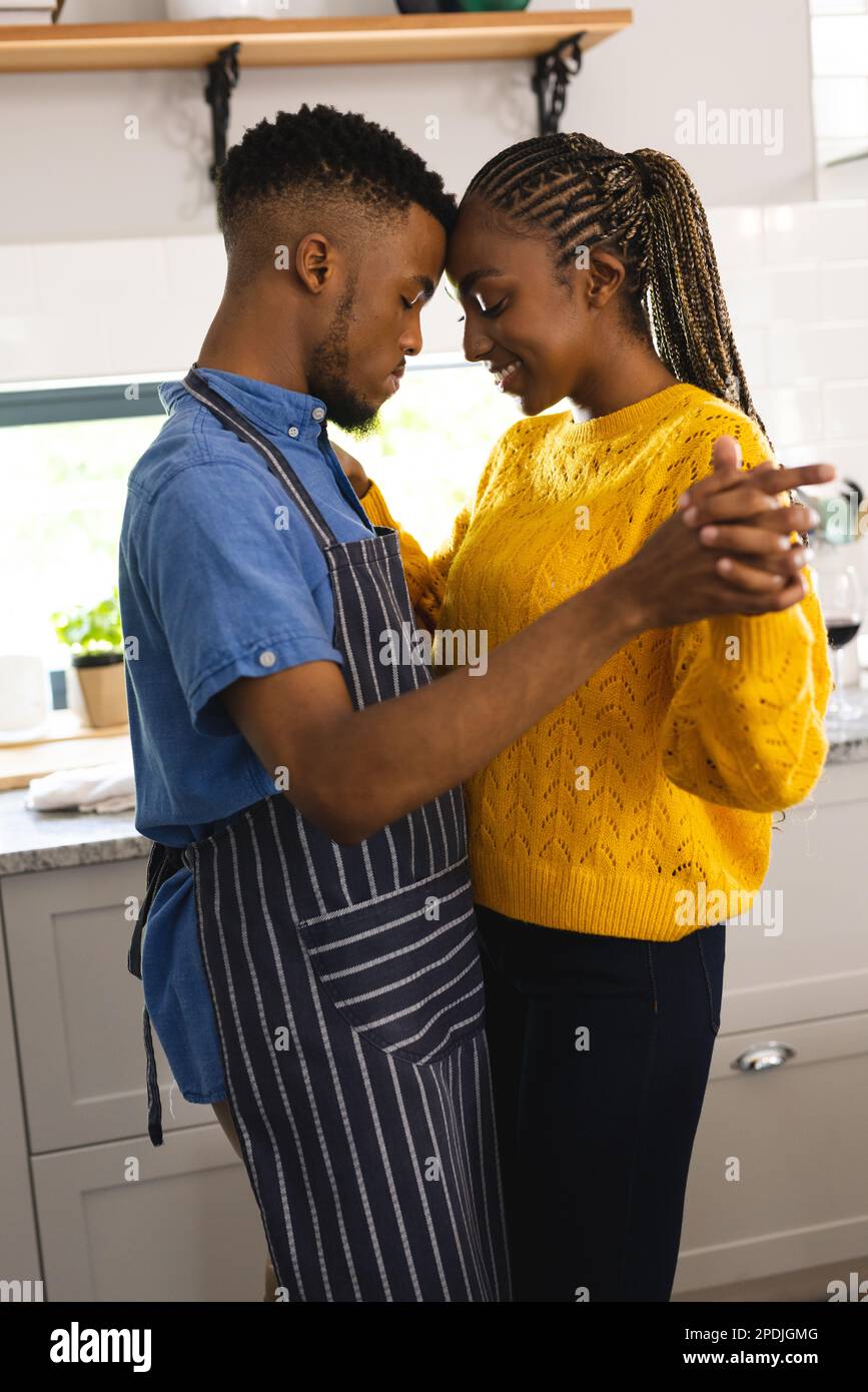 Happy african american couple holding hands and dancing in kitchen ...