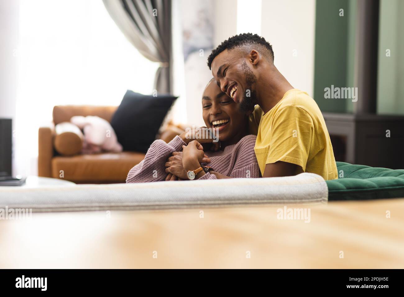 Happy african american couple sitting on sofa and embracing in living ...
