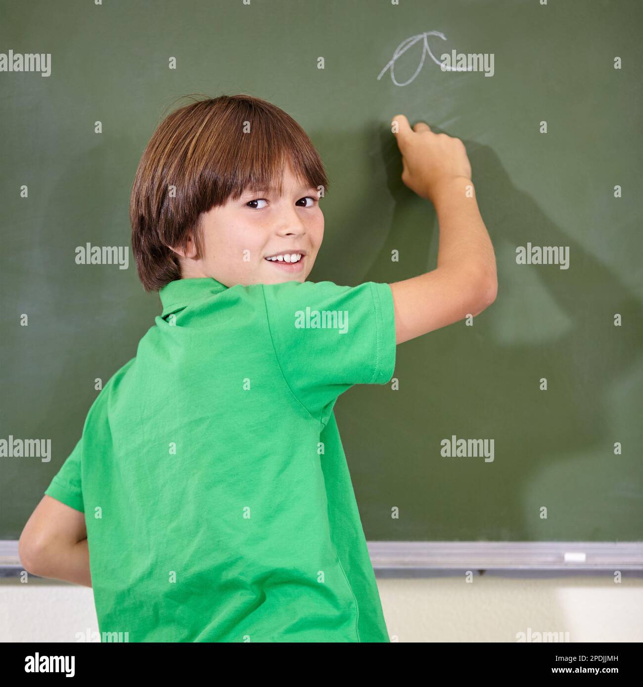 Practicing his handwriting. A little boy writing on the blackboard