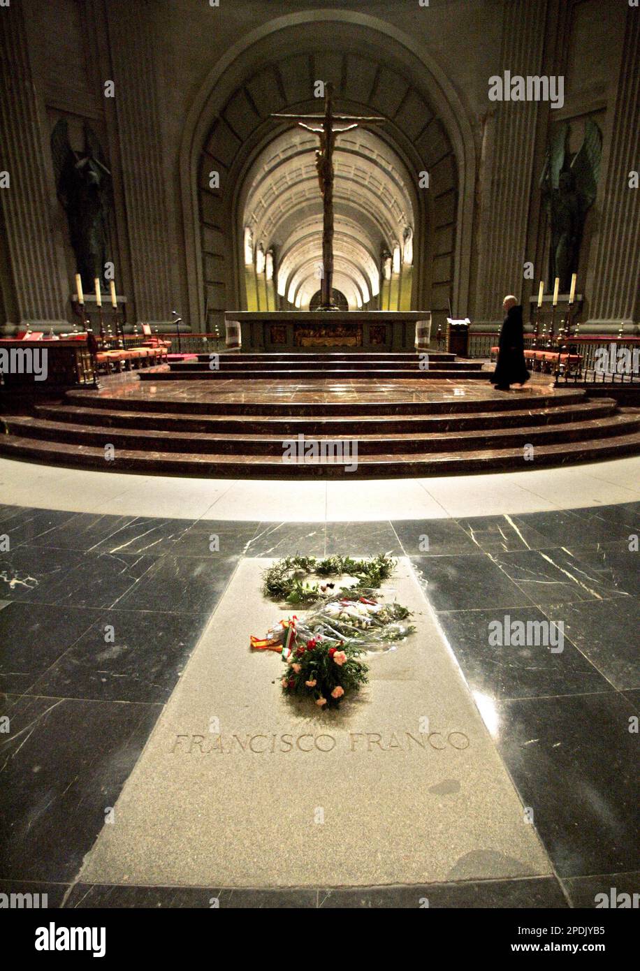 A priest walks accross the altar infront of the tomb of Spain's