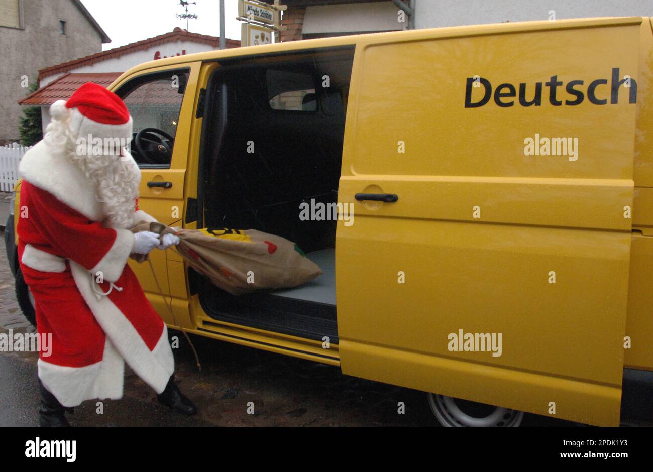 Ein Weihnachtsmann wuchtet seinen Sack voller Geschenke aus dem Auto