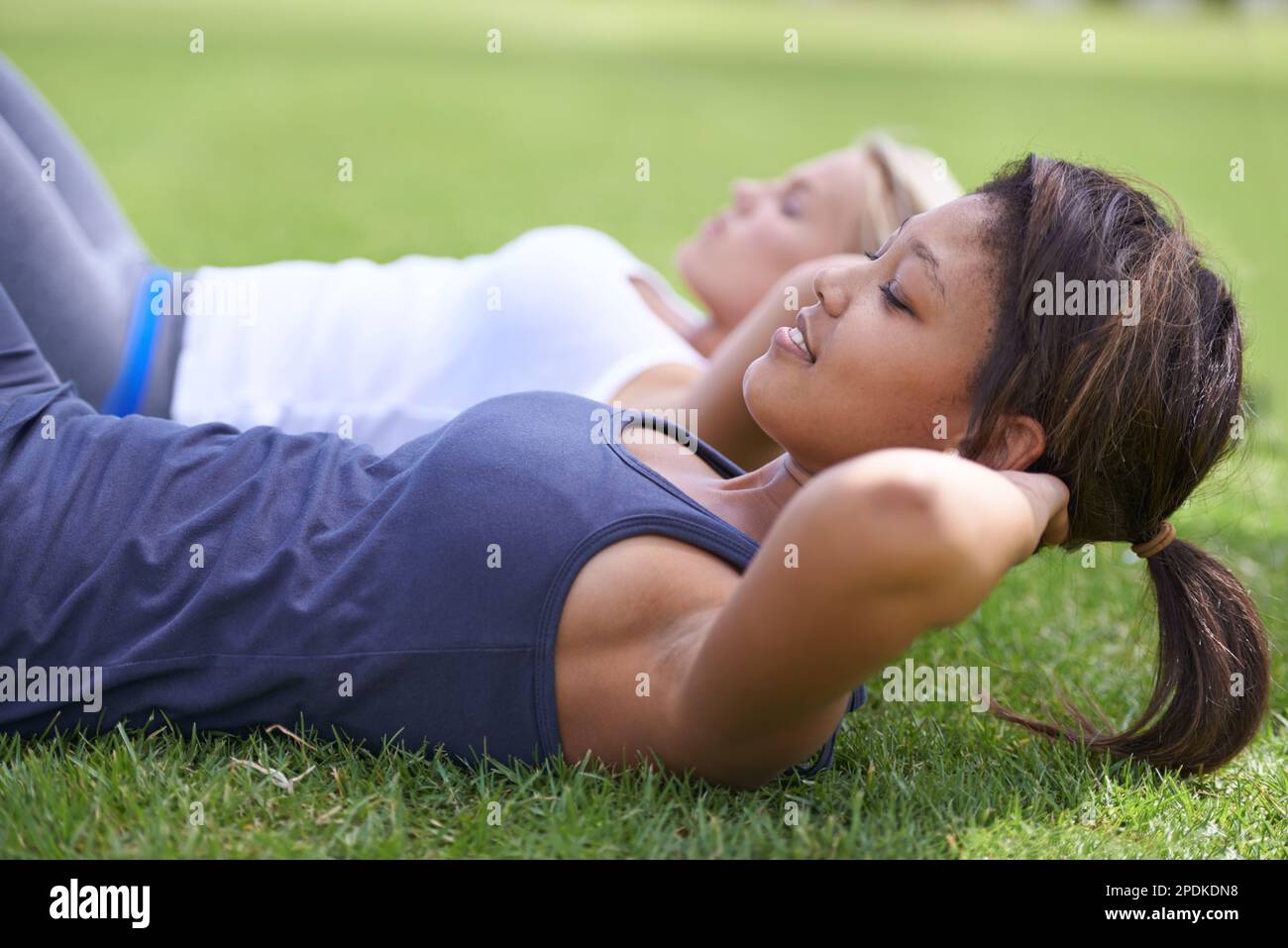 Work those abs. young women doing sit ups on the grass outside Stock ...
