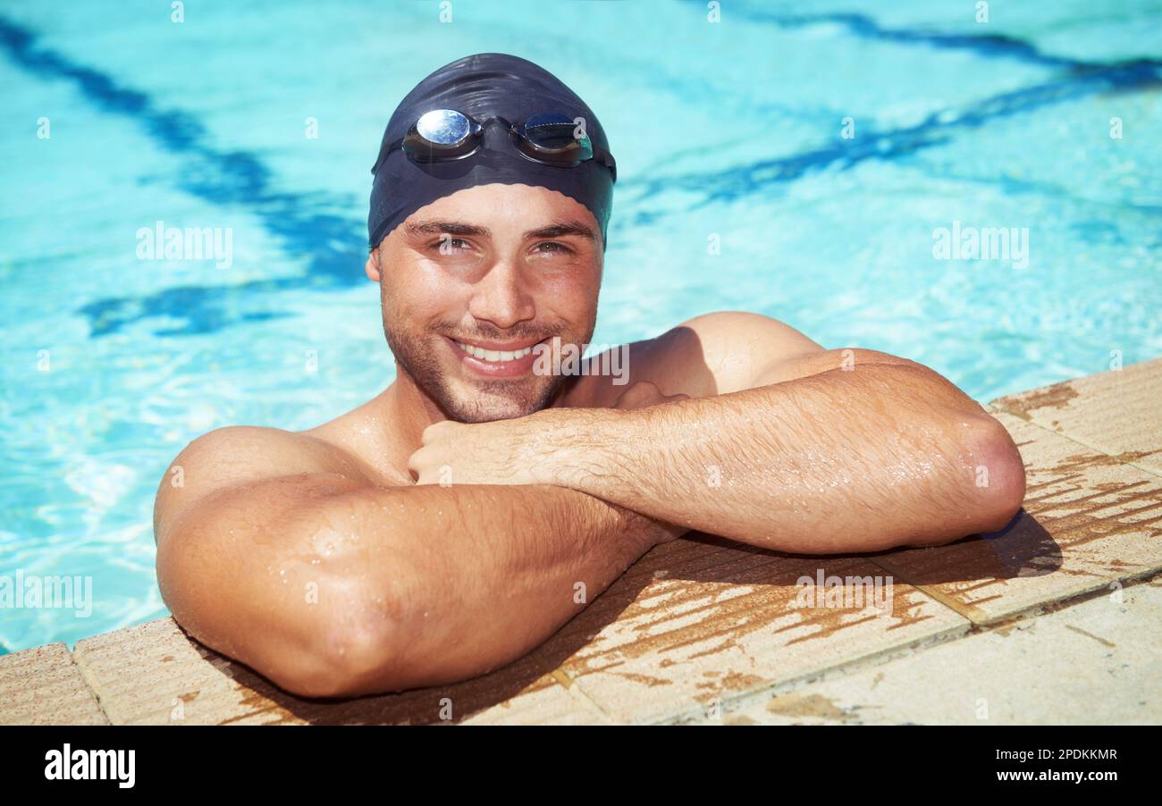 Feeling good after a long swim. A handsome young swimmer wearing goggles and a swimming cap. Stock Photo