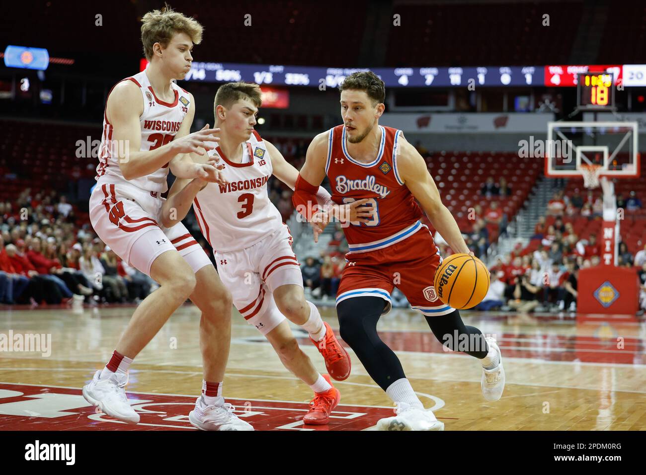 Madison, WI, USA. 14th Mar, 2023. Bradley Braves guard Ville Tahvanainen (23) drives against Wisconsin Badgers guard Connor Essegian (3) and forward Markus Ilver (35) during the NCAA basketball NIT First Round game between the Bradley Braves and the Wisconsin Badgers at the Kohl Center in Madison, WI. Darren Lee/CSM/Alamy Live News Stock Photo