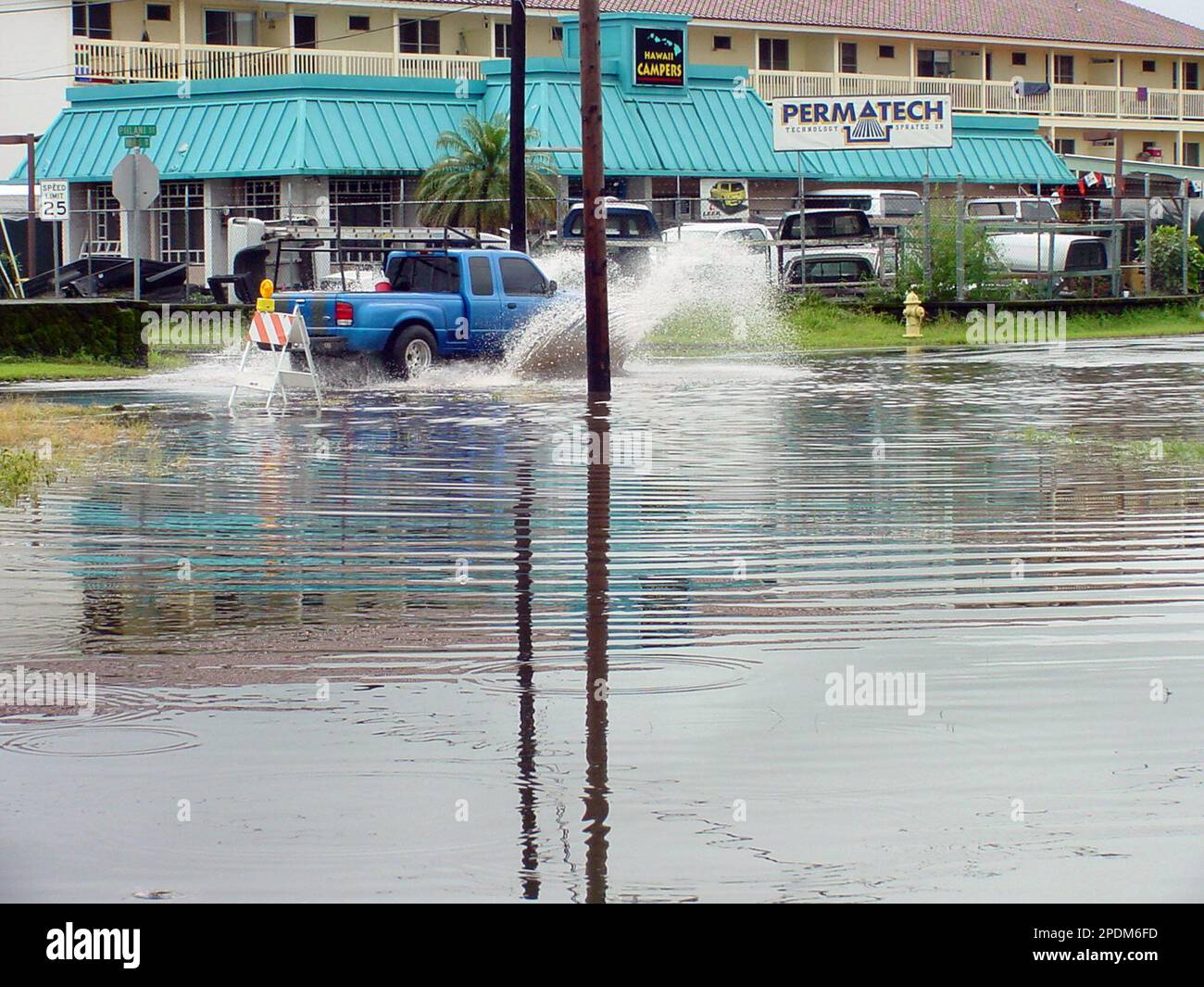 A pick up truck creates a small wave of water as it enters a flooded ...