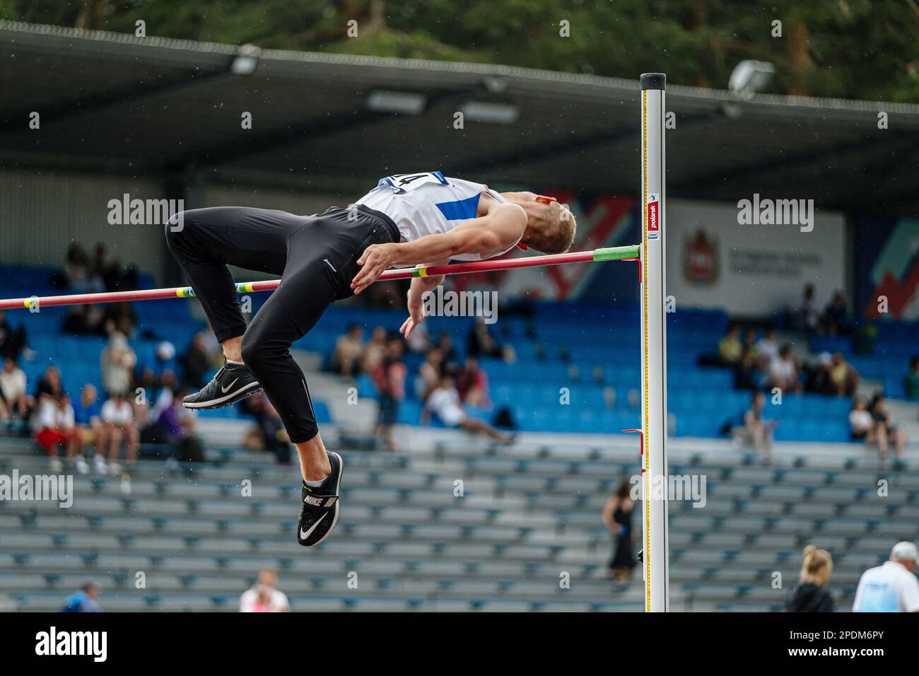 male athlete jumper high jump in rain, athletics competition, Nike