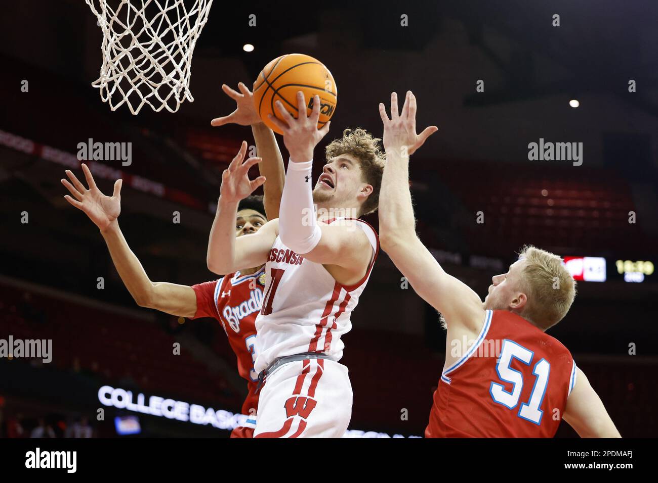Madison, WI, USA. 14th Mar, 2023. Wisconsin Badgers guard Max Klesmit (11) makes a layup between Bradley Braves forward Darius Hannah (35) and forward Rienk Mast (51) during the NCAA basketball NIT First Round game between the Bradley Braves and the Wisconsin Badgers at the Kohl Center in Madison, WI. Darren Lee/CSM/Alamy Live News Stock Photo