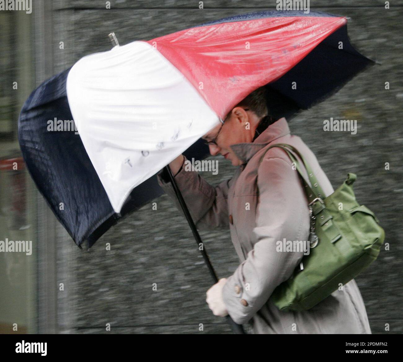 A woman walking in downtown Brooklyn struggles with her umbrella as