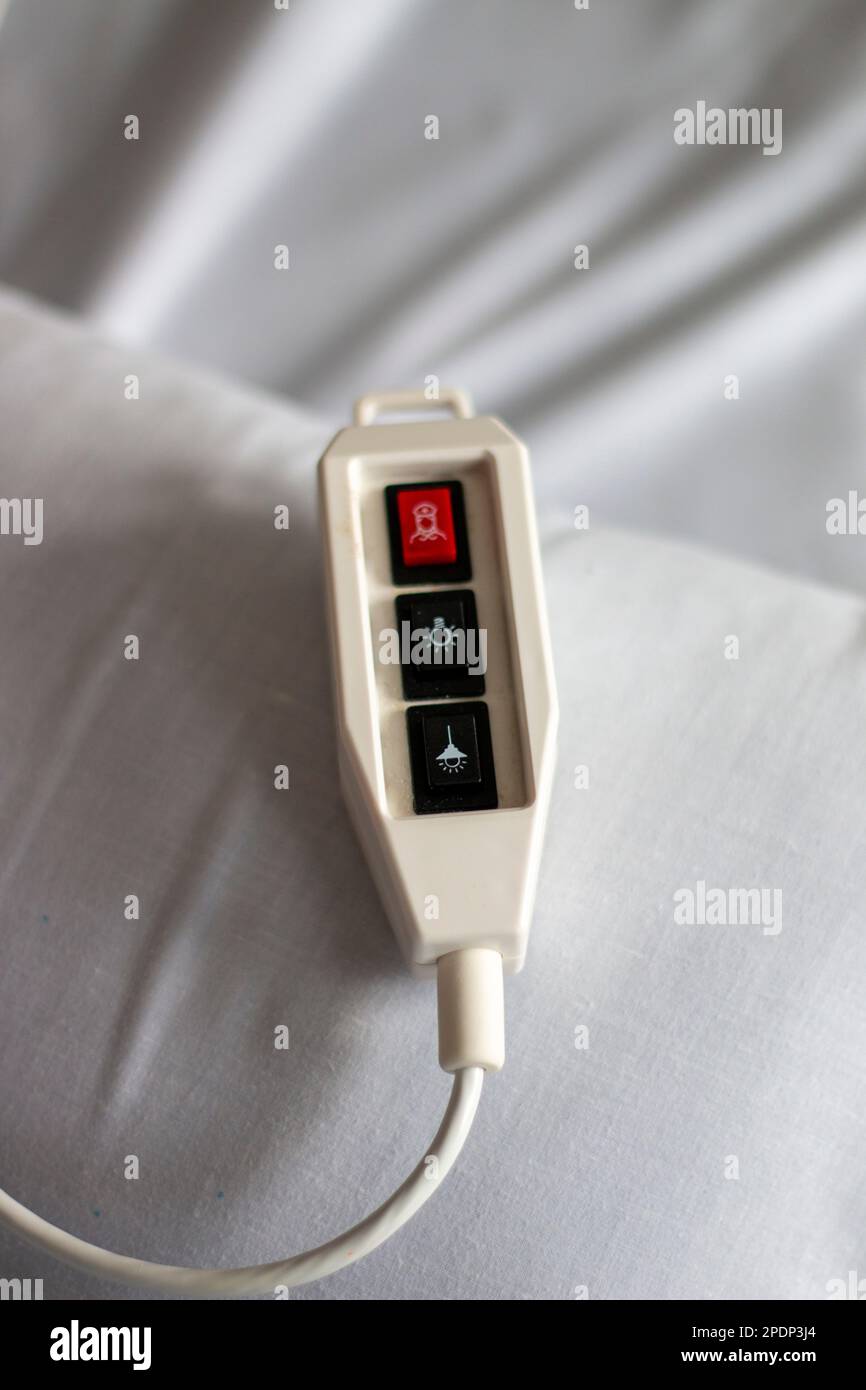 Hospital call control with a red emergency button resting on a bed with