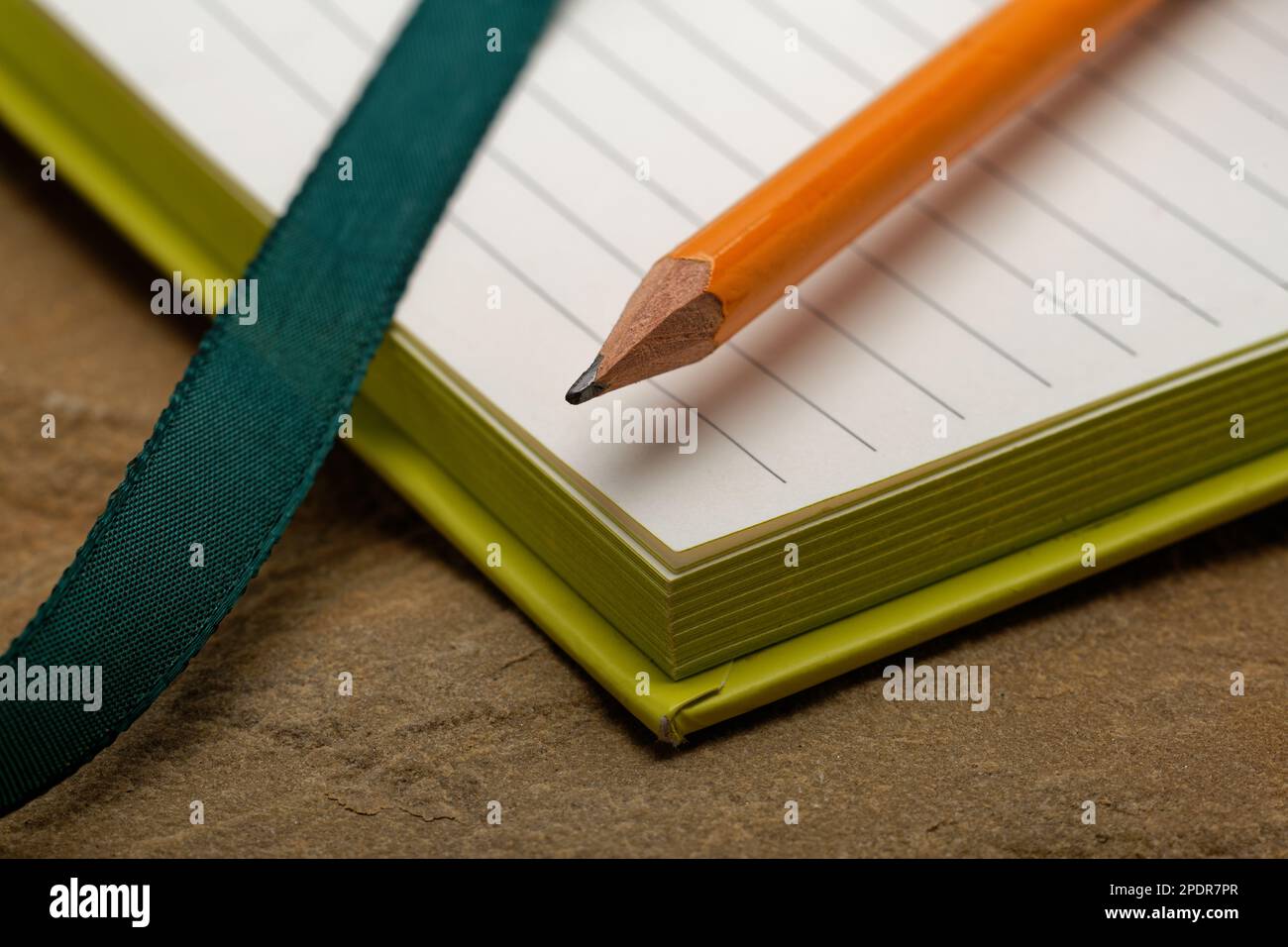 A lined notebook with a pencil. Ready to take notes, sketch ideas and write plans. Pencil and paper at the ready. Stock Photo