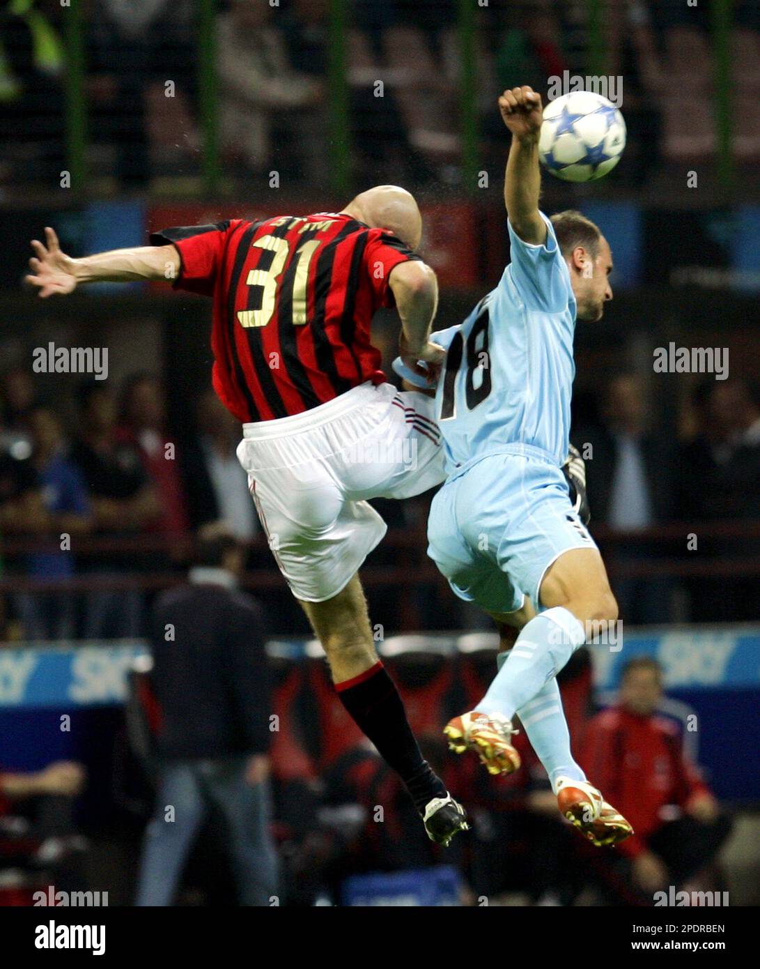 AC Milan defender Jaap Stam, left, of the Netherlands jumps for the ball  with Lazio forward Tommaso Rocchi during this Italian first division soccer  match at the San Siro stadium in Milan,, image size:1091x1390