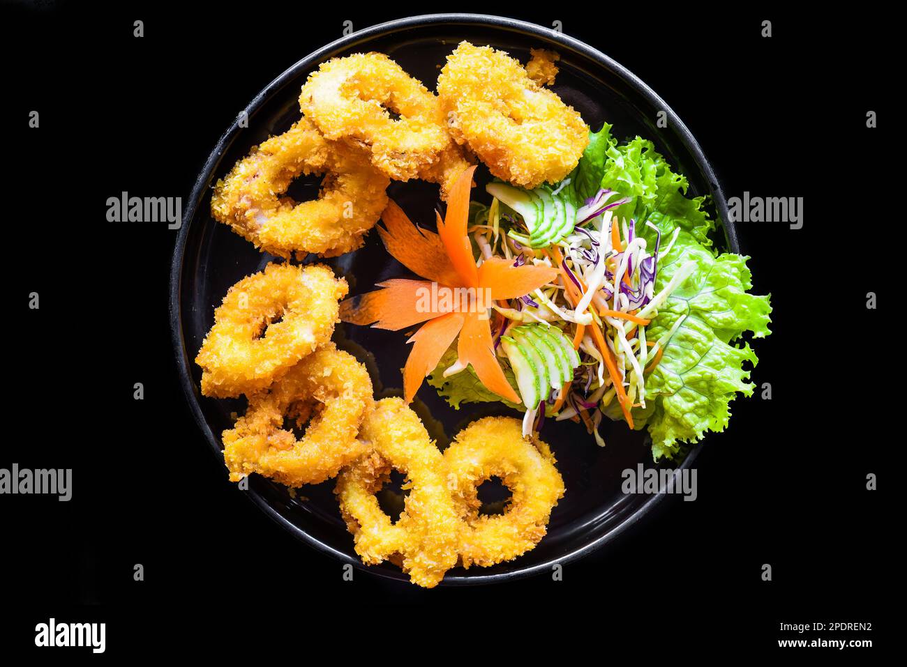 Fried squid or calamari in batter on a black plate close up top view