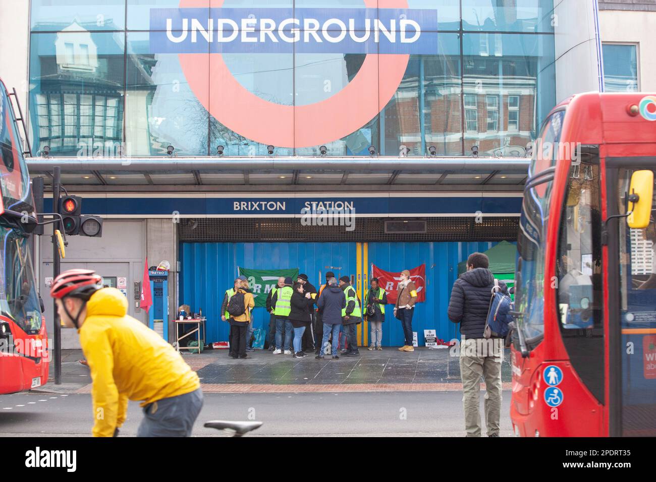 London, UK, 15 March 2023: The RMT and Aslef unions are on strike, completely closing the London Underground today, with a picket line at Brixton station. A cyclist speeds past the station. Other commuters squeezed on to buses but sometimes they arrived too full to take on any more passengers. Anna Watson/Alamy Live News Stock Photo