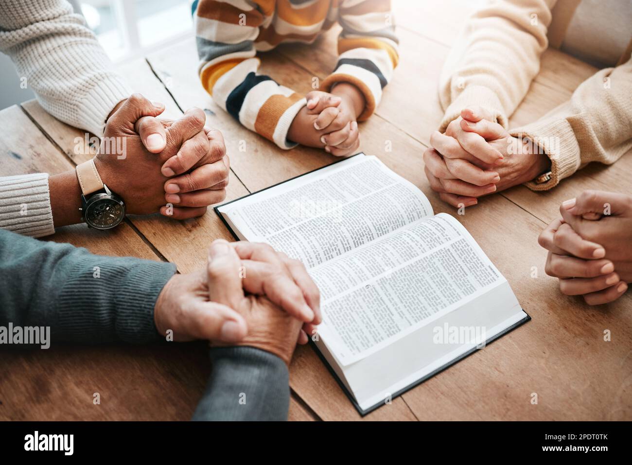 Bible, reading book or hands of big family praying for support or hope in Christian home for worship together. Mother, father or grandparents studying Stock Photo