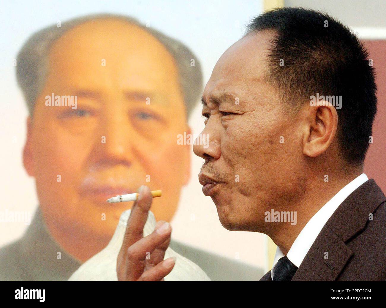 FILE ** A man smokes near a portrait of late communist leader Mao Zedong in  Beijing's Tiananmen Square in this Oct. 29, 2004 file photo. More  middle-aged Chinese are dying of
