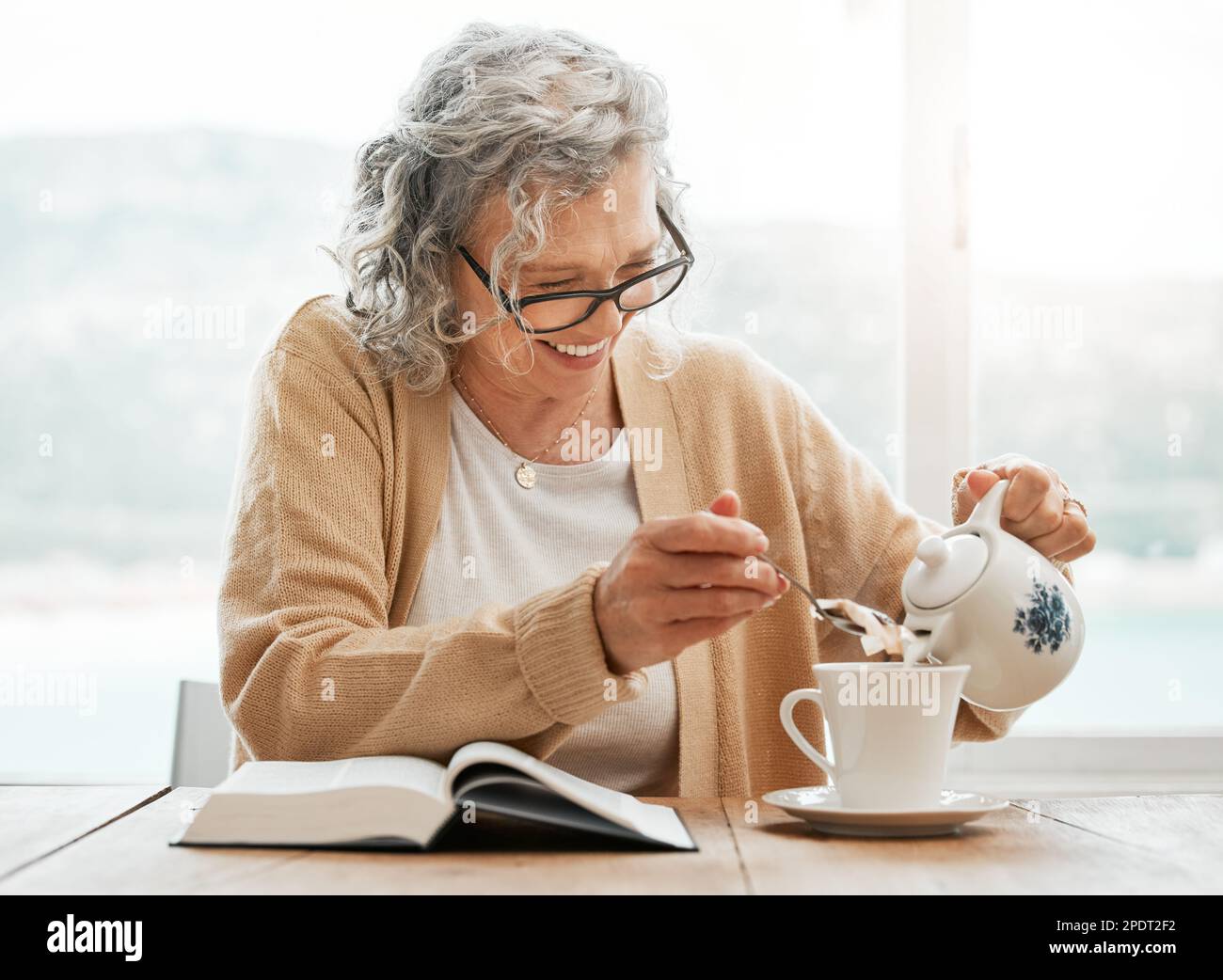 Reading book, tea or funny old woman with smile or hope in Christianity belief or faith relaxing. Bible, laugh or happy catholic senior person Stock Photo