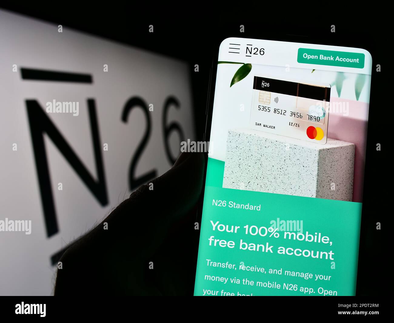 Person holding cellphone with webpage of German financial services company N26 Bank AG on screen with logo. Focus on center of phone display. Stock Photo