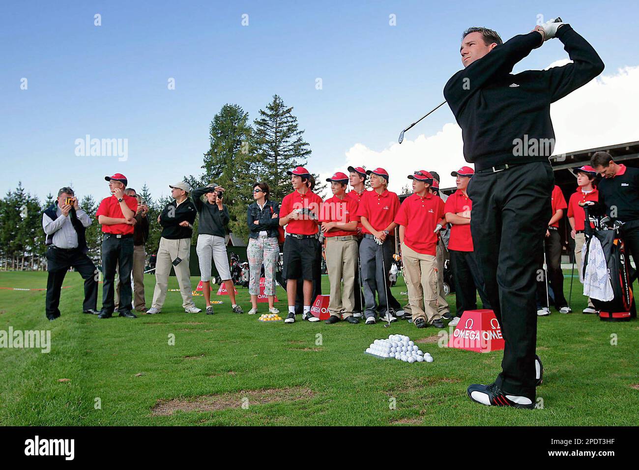 Sergio Garcia from Spain, right, winner of the last Omega European Masters  golf tournament, tees off as he is watched by 18 young golfers from  Switzerland, playing during the "Omega Juniors Challenge"