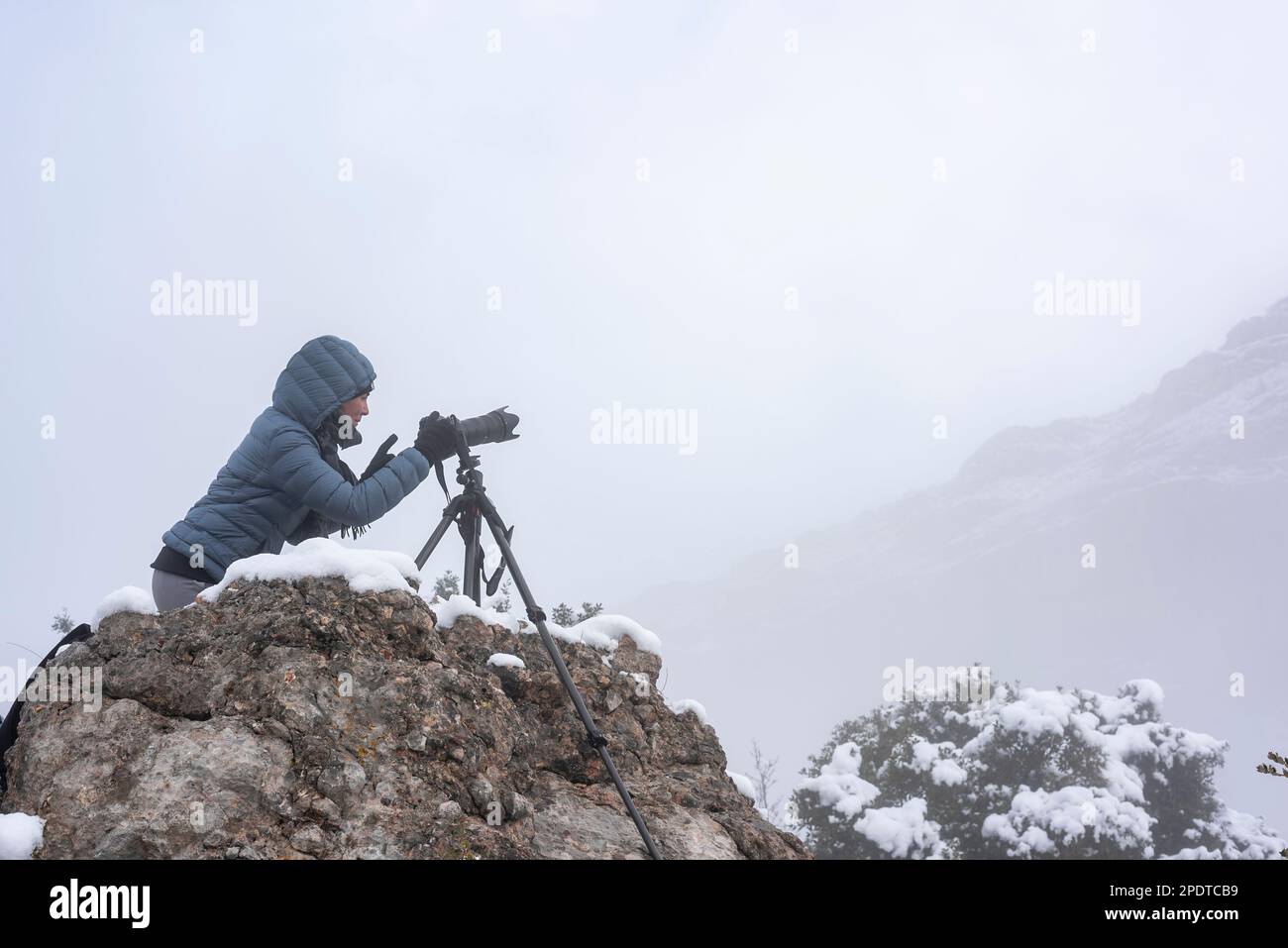 snowy day with this horizontal shot featuring a woman taking photographs, providing ample copy space for your winter-themed content Stock Photo