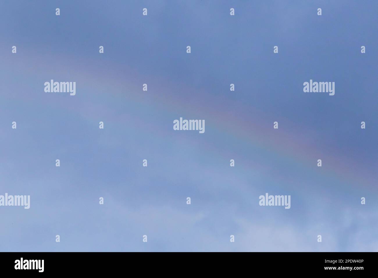 close up of rainbow in a cloudy sky at rain Stock Photo