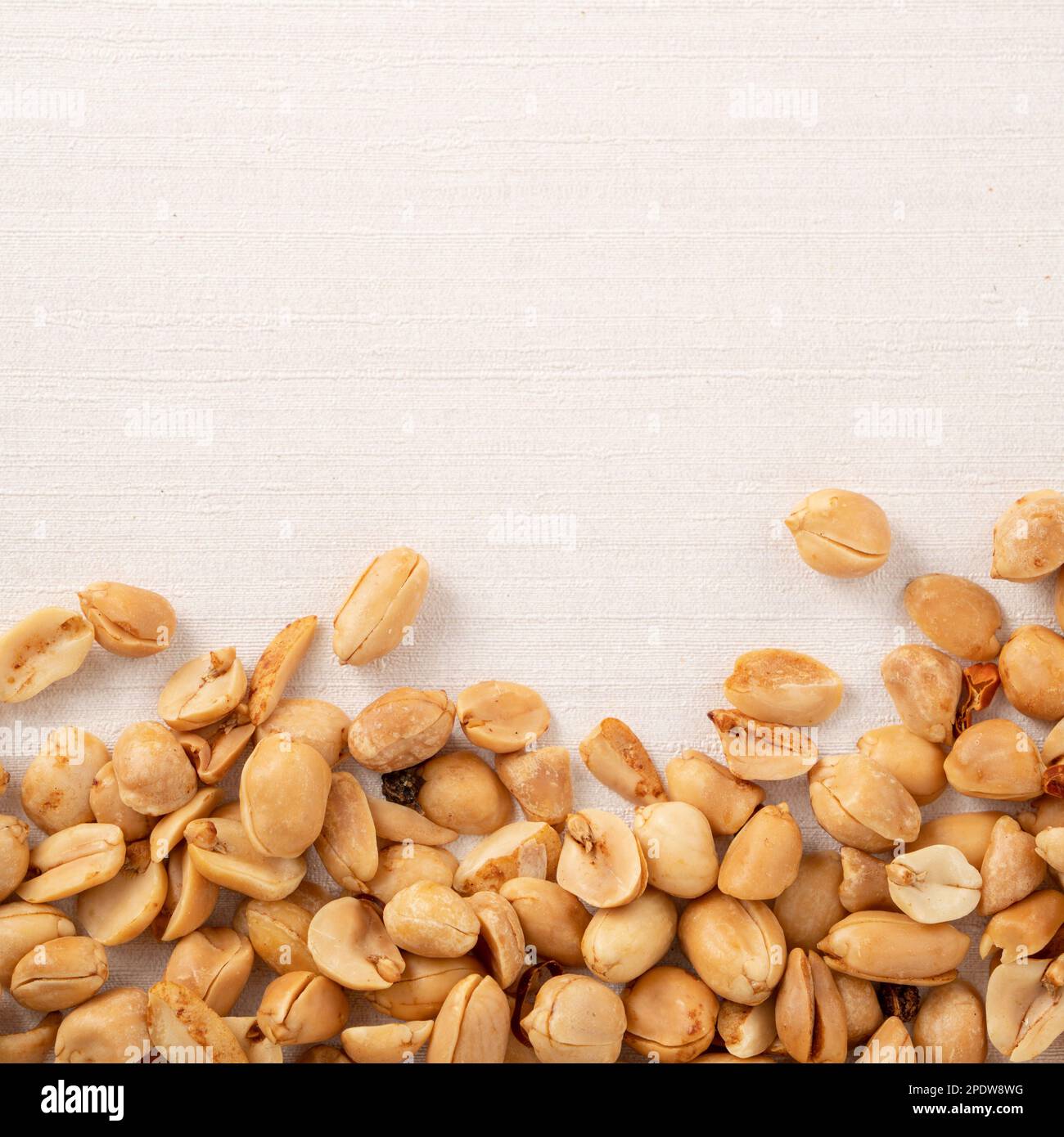 Spicy flavored peanut kernel spilling on white table background. Stock Photo
