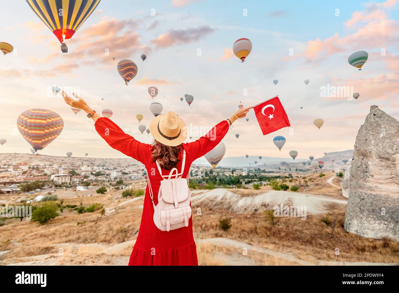 Join a young woman as she watches the iconic hot air balloons of Cappadocia, Turkey while proudly displaying the Turkish flag. A celebration of the co Stock Photo