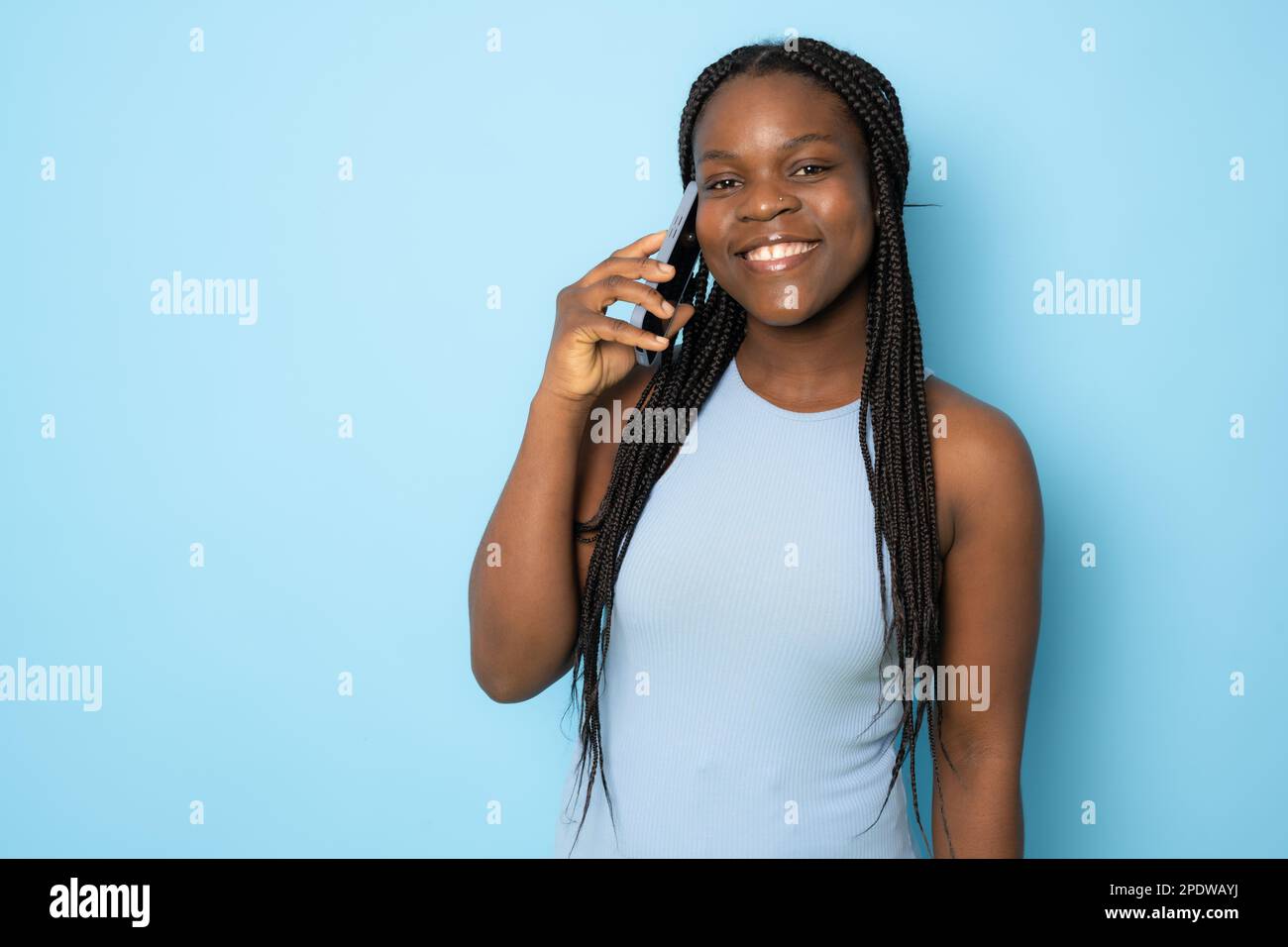 Portrait of young cheerful black lady using Smartphone For Messaging With Friends, Happy African American Lady Texting On Cellphone while standing Ove Stock Photo