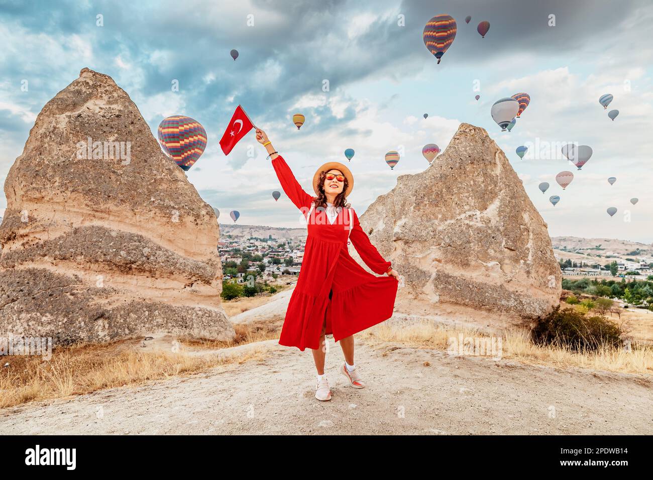 Get a glimpse of Cappadocia's breathtaking landscapes through the eyes of a young woman as she watches the hot air balloons soar and displays the Turk Stock Photo