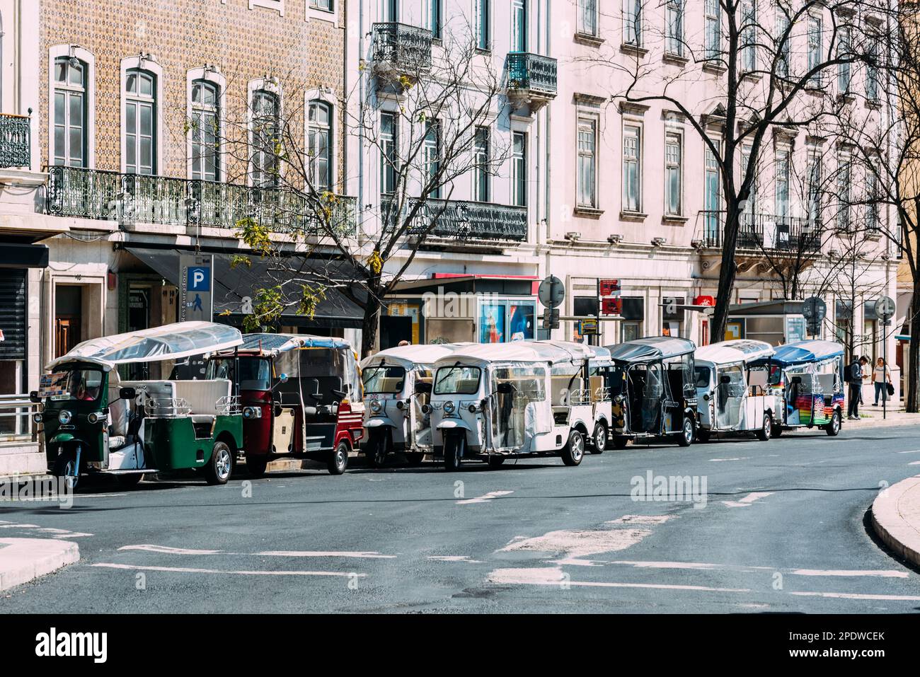 Lisbon, Portugal - March 12, 2023: Tuk-tuk cars of various liveryes waiting for clients on a street of Lisbon city, Portugal Stock Photo