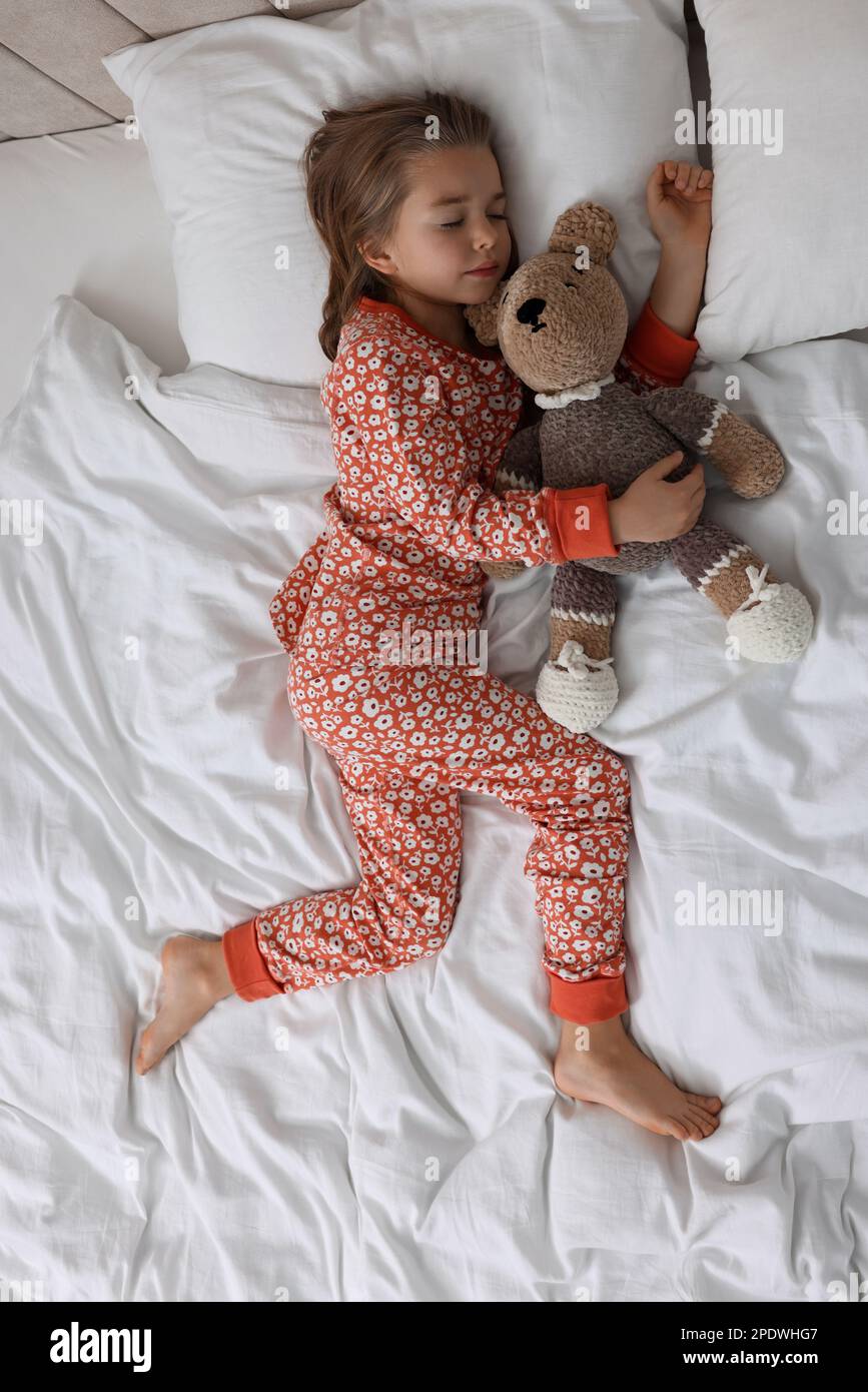 Cute little girl with toy bear sleeping on bed, top view Stock Photo ...