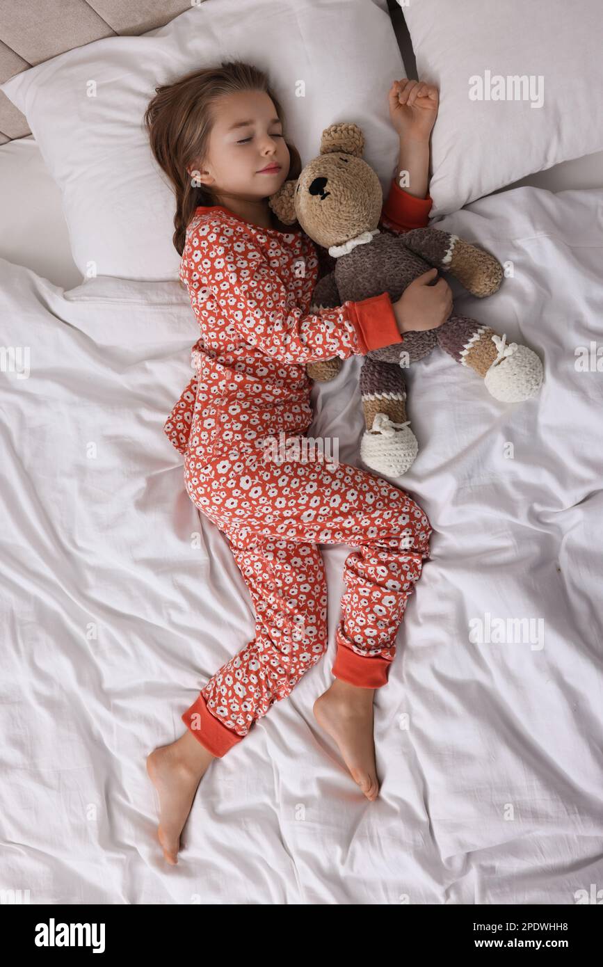 Cute little girl with toy bear sleeping on bed, top view Stock Photo ...
