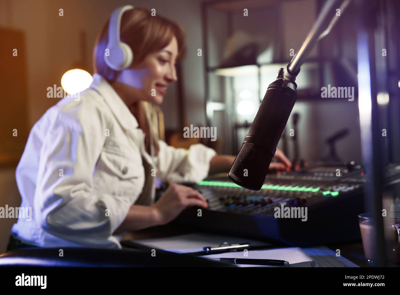 Woman working as radio host in modern studio, focus on microphone ...