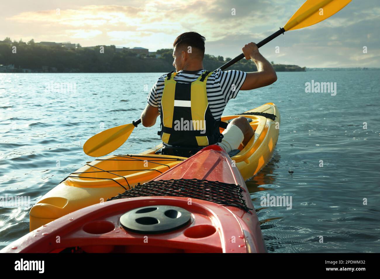 Man in life jacket kayaking on river, back view. Summer activity Stock