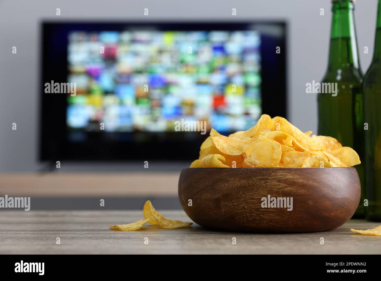 Modern TV set indoors, focus on table with chips and beer Stock Photo