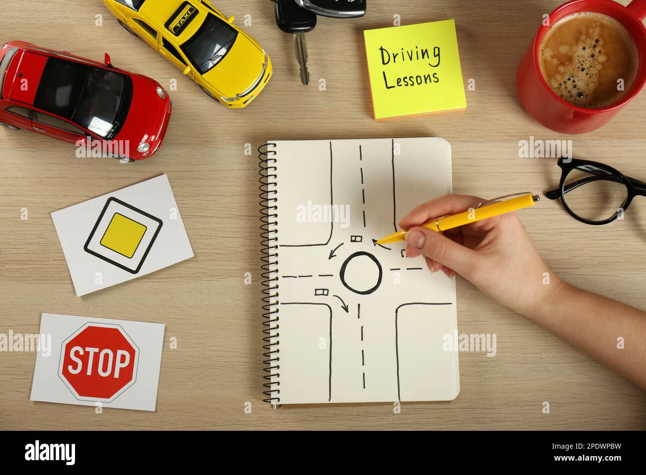 Woman with workbook for driving lessons and road signs at wooden table ...