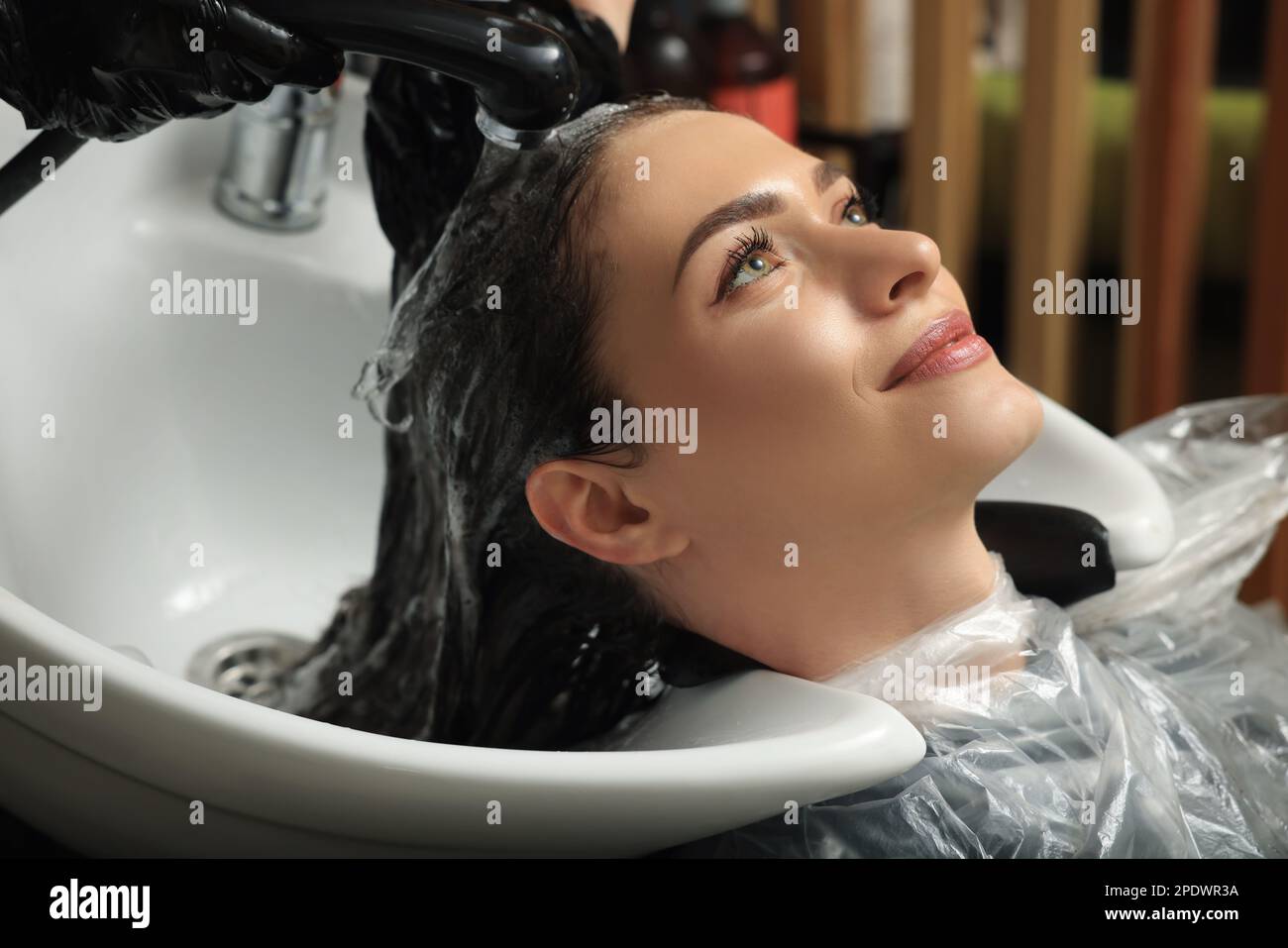 Hairdresser rinsing out dye from woman's hair in beauty salon Stock