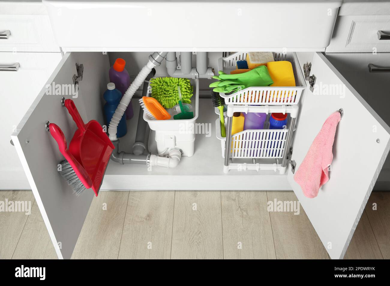 Different cleaning tools and supplies in open under sink Stock