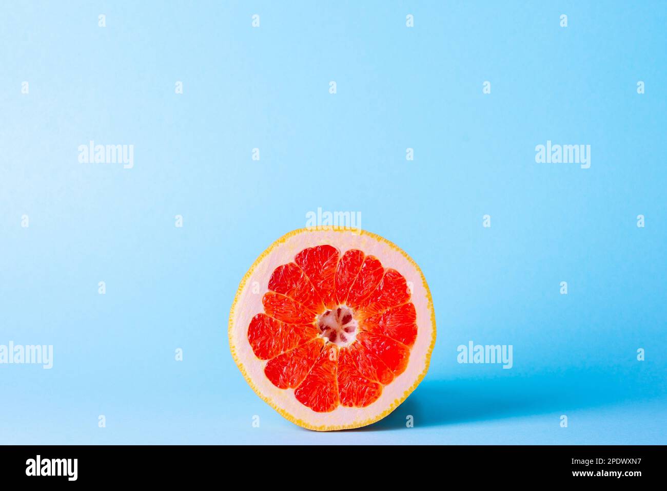 Grapefruit on a blue background. Exotic fruit for diet. Juicy slice of ripe grapefruit. Stock Photo