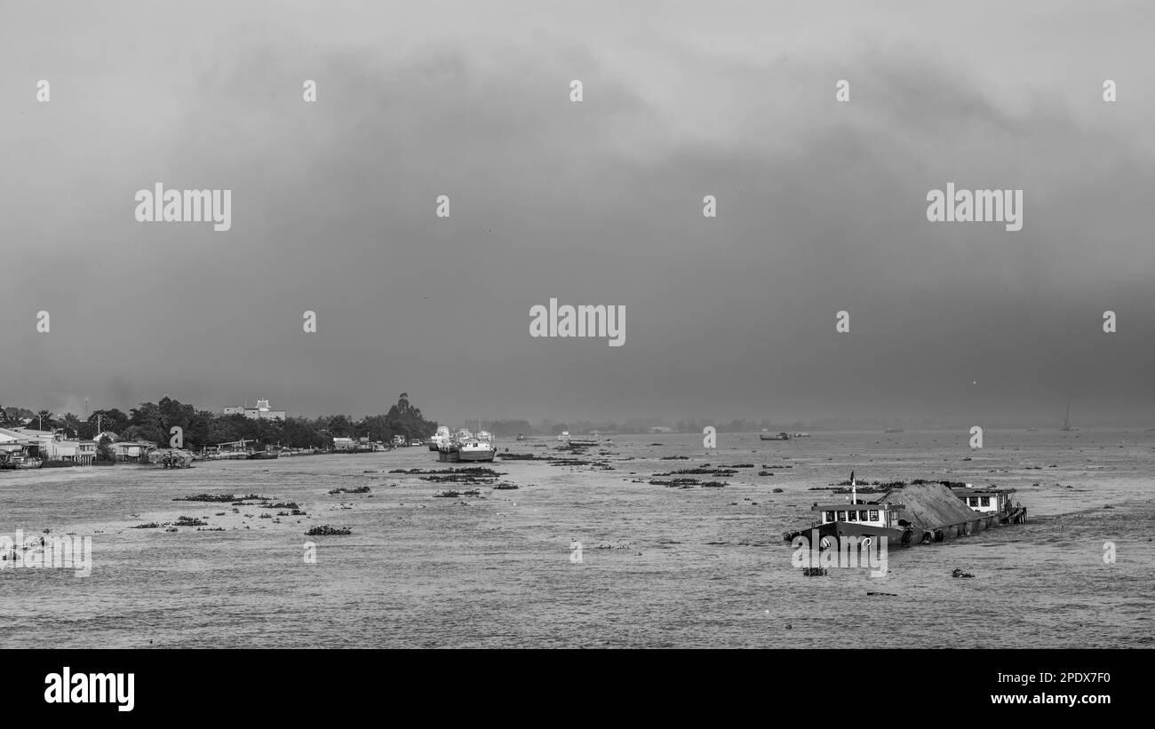 A pall of smoke from brick kilns hangs over the Mekong River as a loaded motorised barge makes it way down river near Long Xuyen, in the Meklong Delta Stock Photo