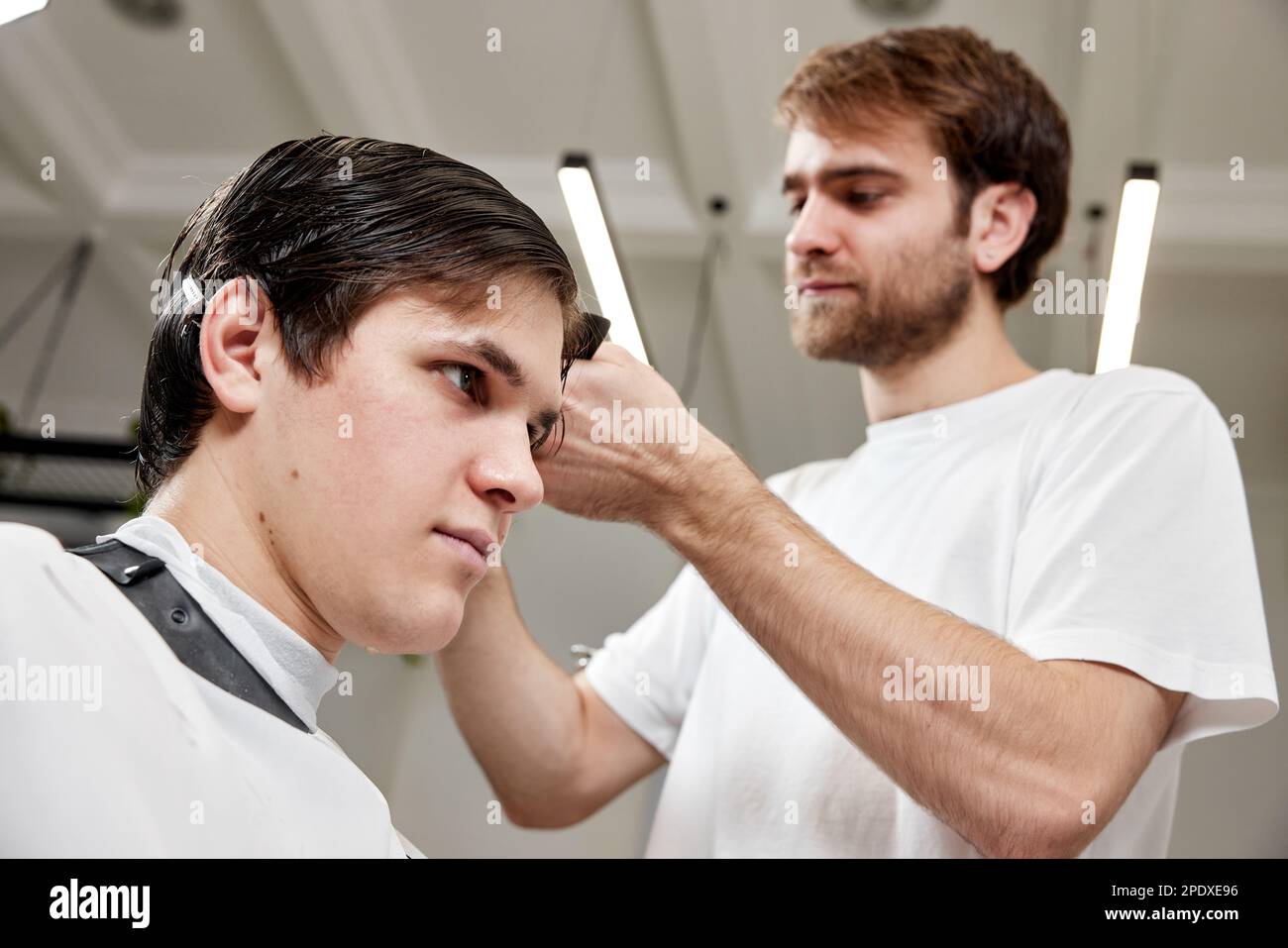 Barber talking to caucasian man while sitting in chair Stock Photo