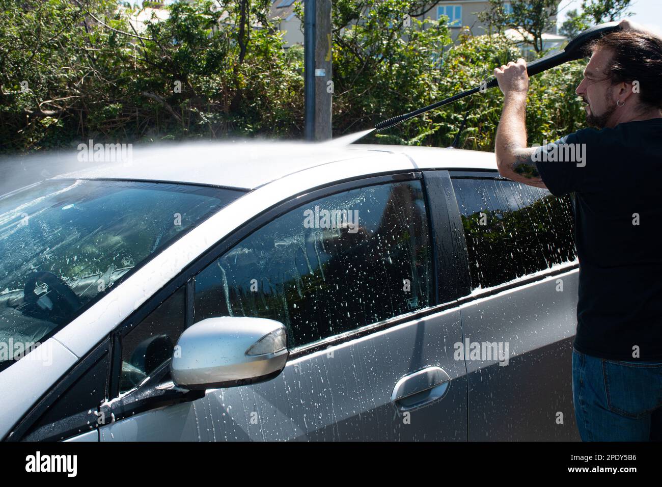 two measles cleaning a silver car spraying foam with a pressure washer