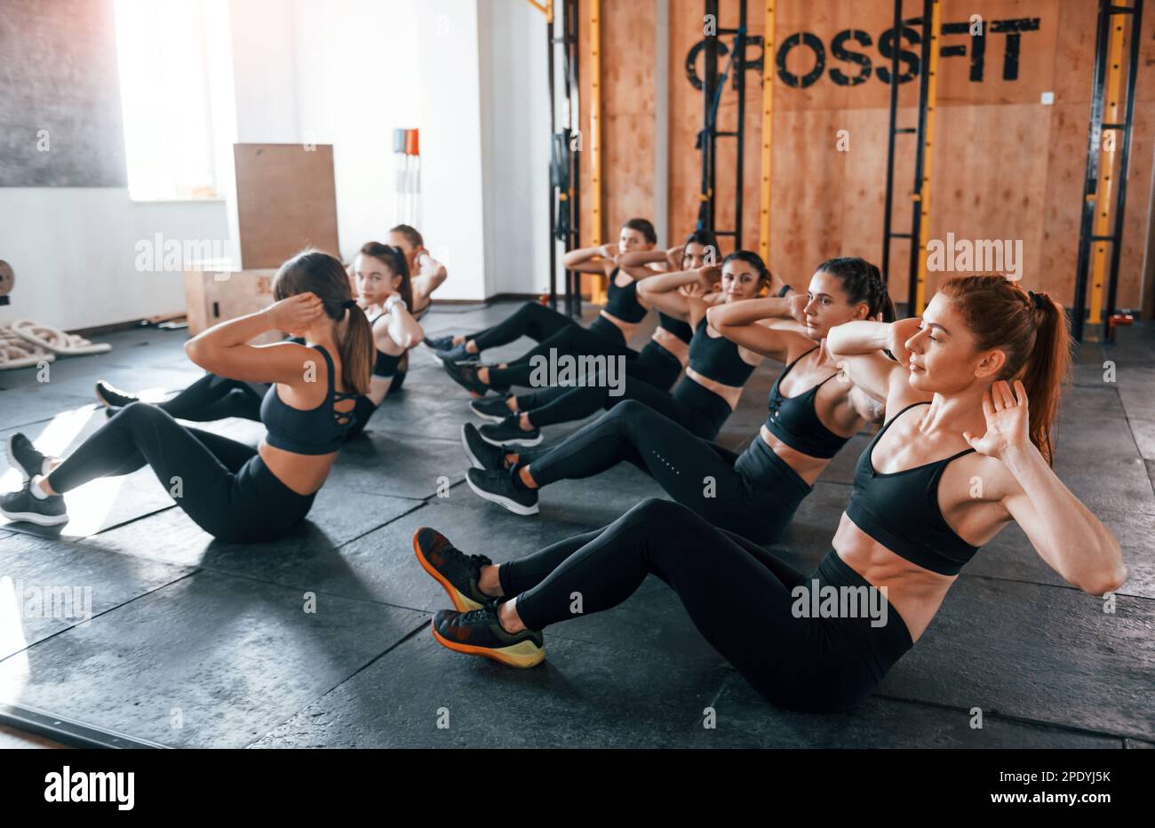 Doing abs. Group of young sportive people have crossfit day indoors in