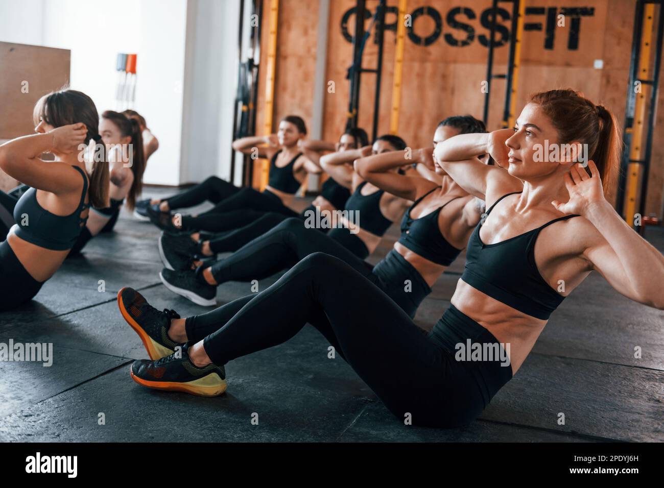 Doing abs. Group of young sportive people have crossfit day indoors in