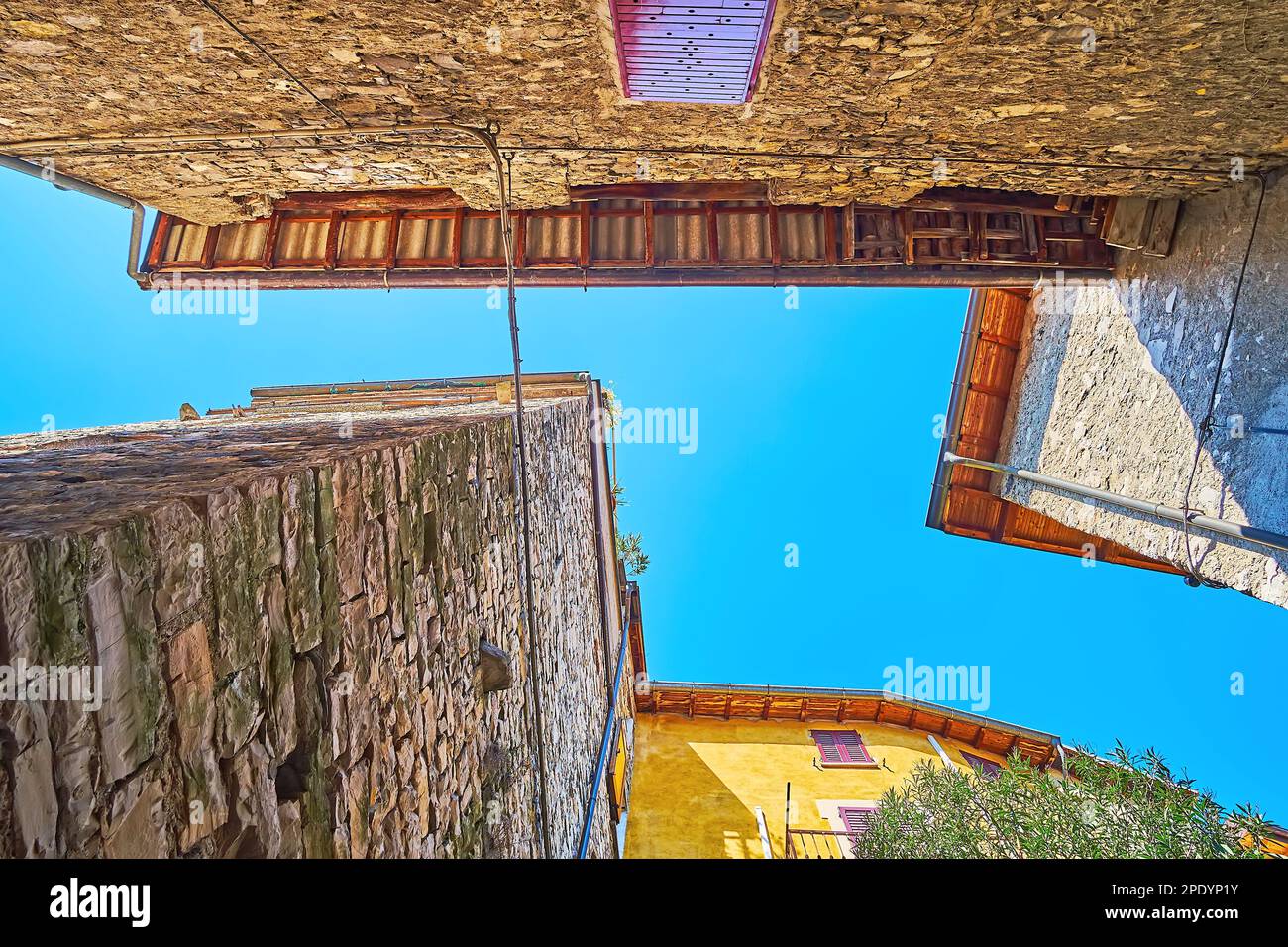 The stone walls and blue sky between old houses, Albogasio, Valsolda, Italy Stock Photo