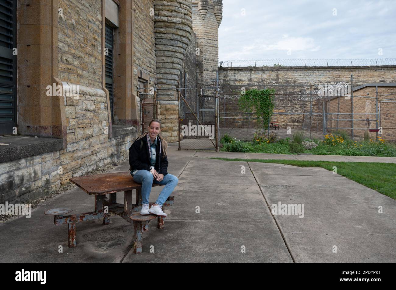 A young girl sitting at a table in the main courtyard of Old Joliet Prison, a former abandoned jail Stock Photo