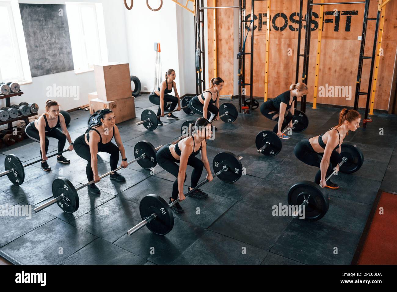 Squats with barbell. Group of young sportive people have crossfit